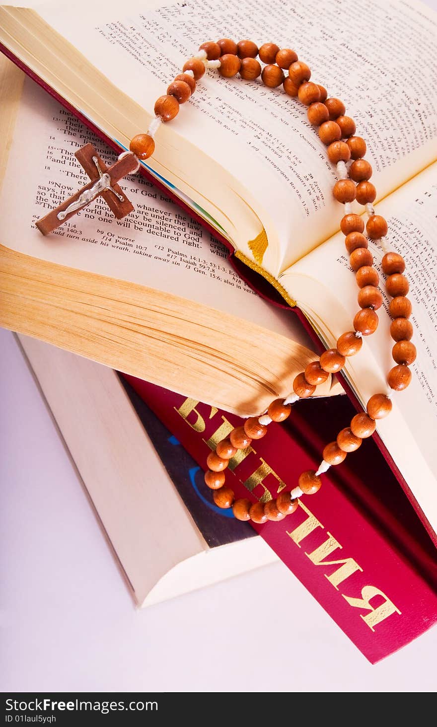 Open Holy Bible lying on stack of old books with glasses, cross and beads. Open Holy Bible lying on stack of old books with glasses, cross and beads