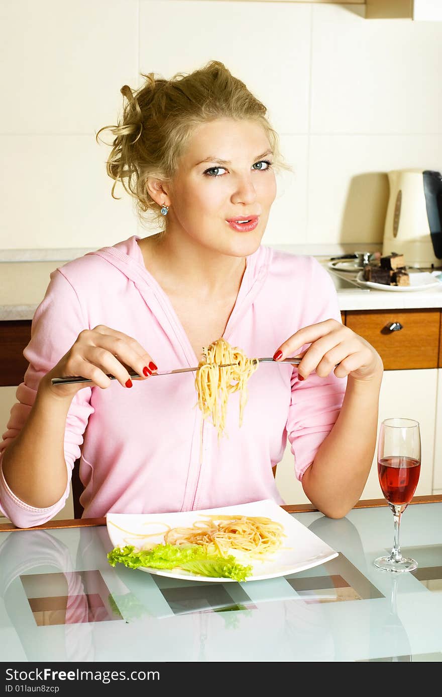 Happy beautiful woman at home in the kitchen eating spaghetti. Happy beautiful woman at home in the kitchen eating spaghetti