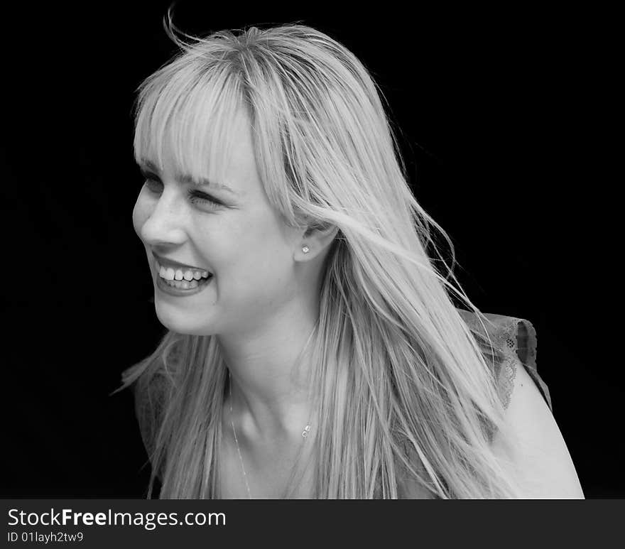 Black and White Portrait of a blond attractive woman smiling against black background