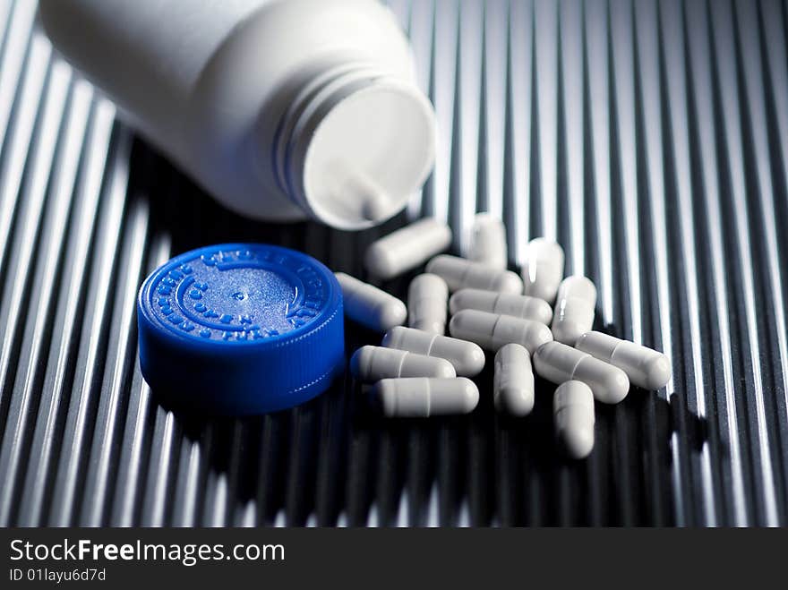 Prescription bottle and capsules on black surface. Prescription bottle and capsules on black surface