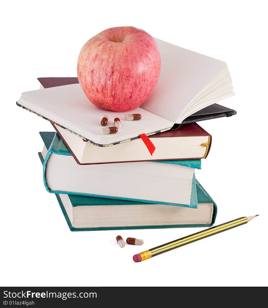 Pills and red apple on textbook pile as metaphor of efective learning. Pills and red apple on textbook pile as metaphor of efective learning