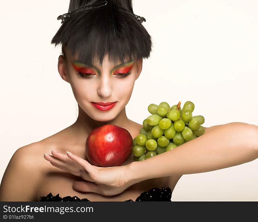 Portrait of pretty brunette with red apple and green grapes. Portrait of pretty brunette with red apple and green grapes