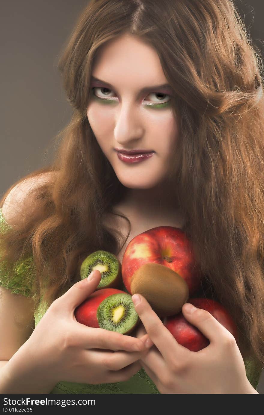 Portrait of young girl witn apples and kiwi in her hands. Portrait of young girl witn apples and kiwi in her hands