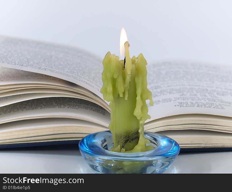 Candle and book on light background