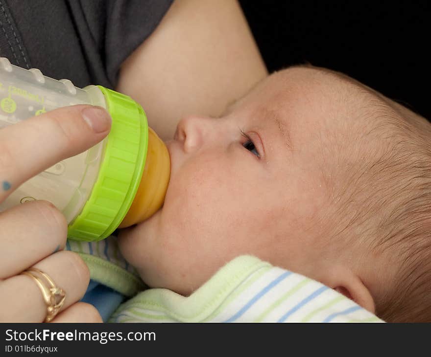 Newborn baby boy, wrapped in blanket, being bottle-fed. Newborn baby boy, wrapped in blanket, being bottle-fed