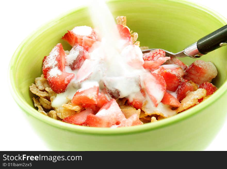 Bowl of corn flakes and fresh strawberries with milk being poured over them. Bowl of corn flakes and fresh strawberries with milk being poured over them.