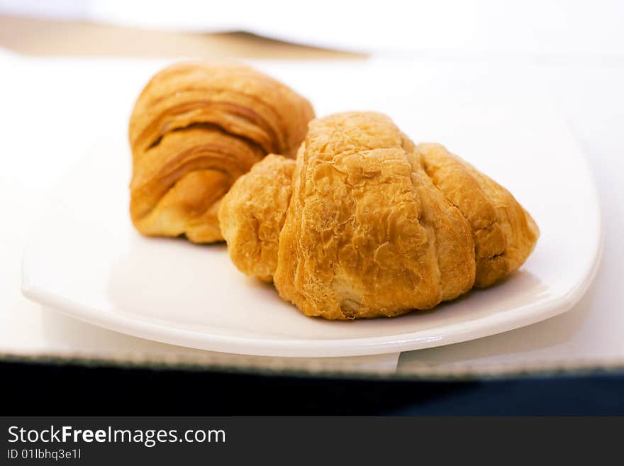 Two fresh croissant on white plate  - focus on close one. Two fresh croissant on white plate  - focus on close one