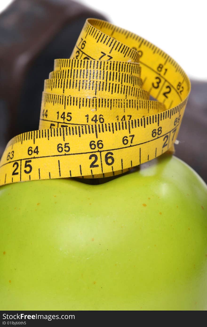 Close up of tape measure on an apple with dumbbells in the background. Close up of tape measure on an apple with dumbbells in the background