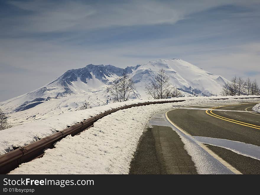 Paved road with snow packed guardrail and mountains. Paved road with snow packed guardrail and mountains