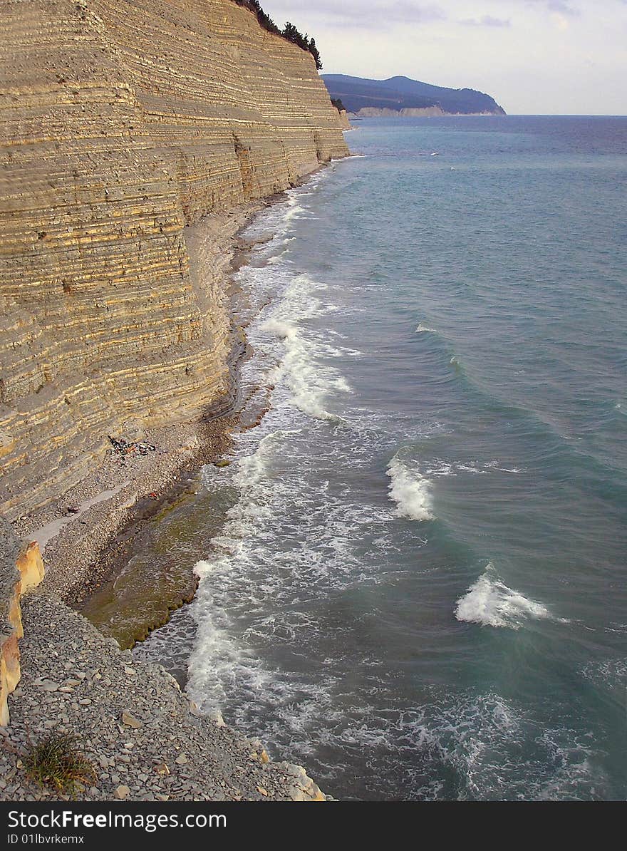 Coast of Black sea about a rock. A kind on a stony beach and the blue sea. Coast of Black sea about a rock. A kind on a stony beach and the blue sea