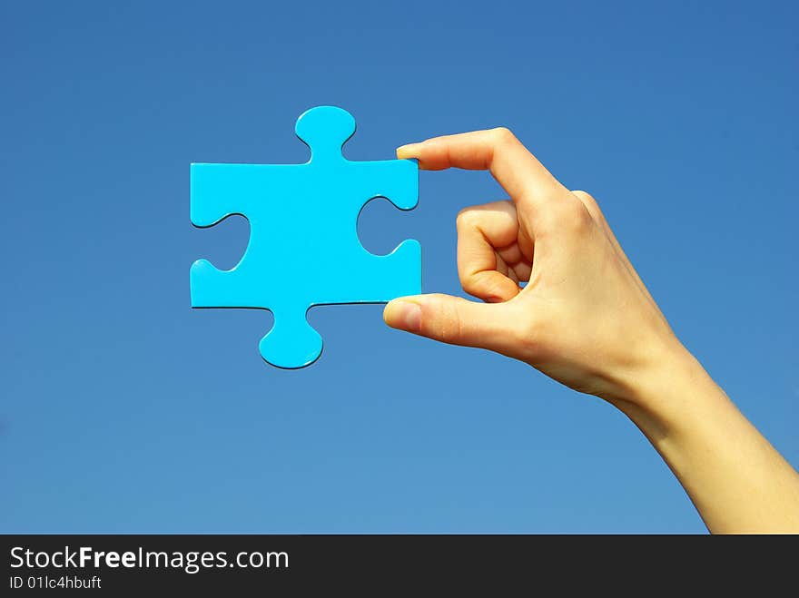 Puzzle in hand isolated on sky background