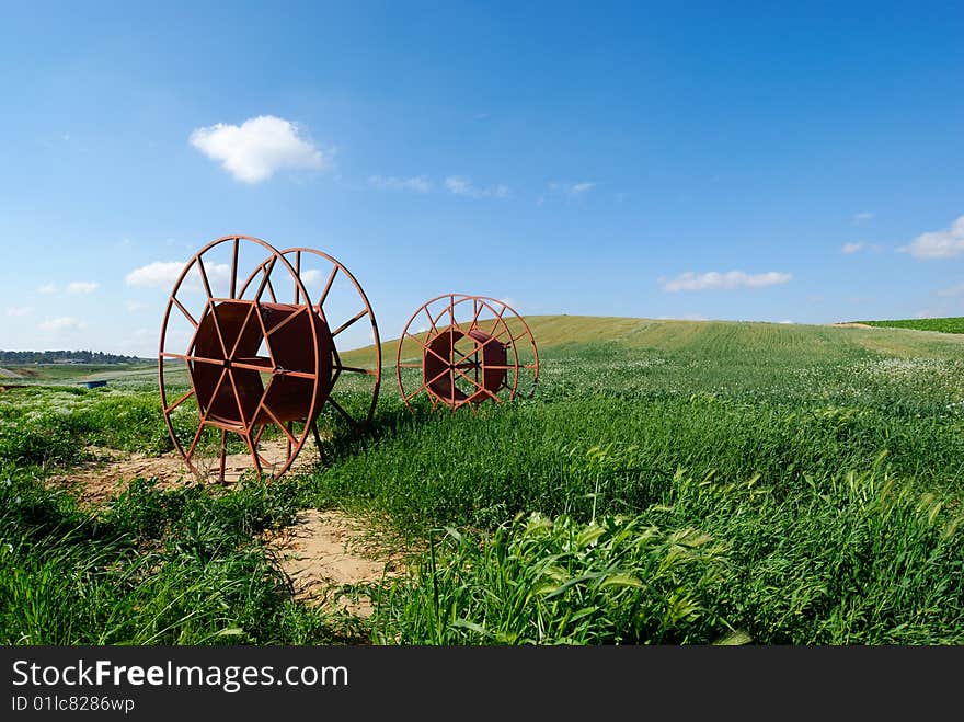 Irrigation tube cylinders on green grass at agricultural farmland. Irrigation tube cylinders on green grass at agricultural farmland