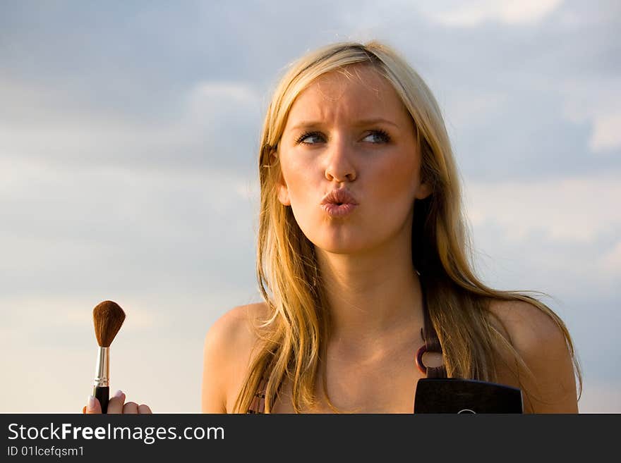 Pretty woman applying makeup. Summer in beach sea. Pretty woman applying makeup. Summer in beach sea.