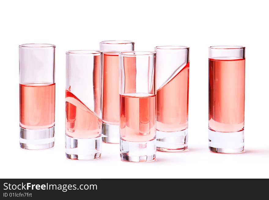 Thin glasses with pink liquid on white background