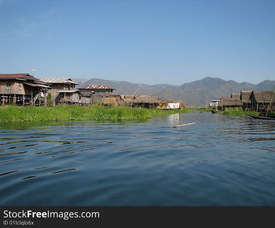 Lakeside village with mountain and blue sky at the background. Myanmar, Burma.