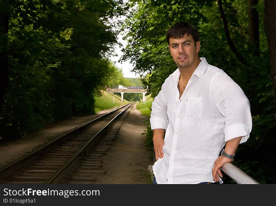 Handsome man in a white shirt against the backdrop of the railway. Handsome man in a white shirt against the backdrop of the railway