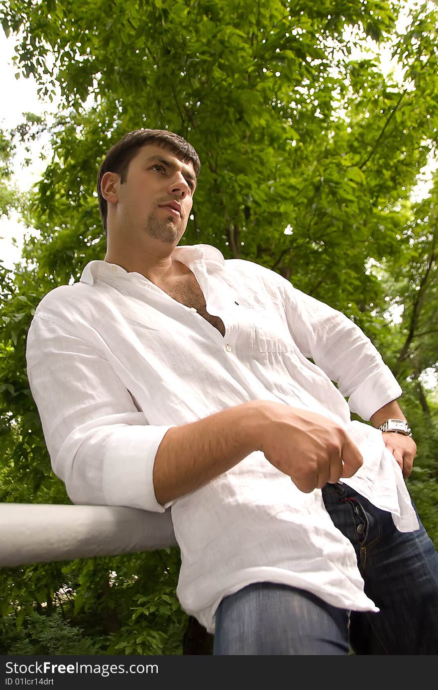 Handsome man in a white shirt against the backdrop of green forest. Handsome man in a white shirt against the backdrop of green forest