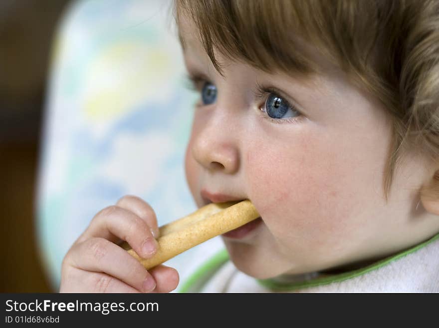 A little blue-eyed child with a piece of bread in the mouth. A little blue-eyed child with a piece of bread in the mouth