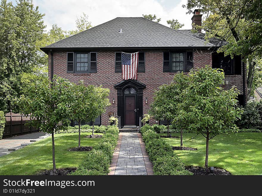 Luxury brick home in suburbs with American flag. Luxury brick home in suburbs with American flag