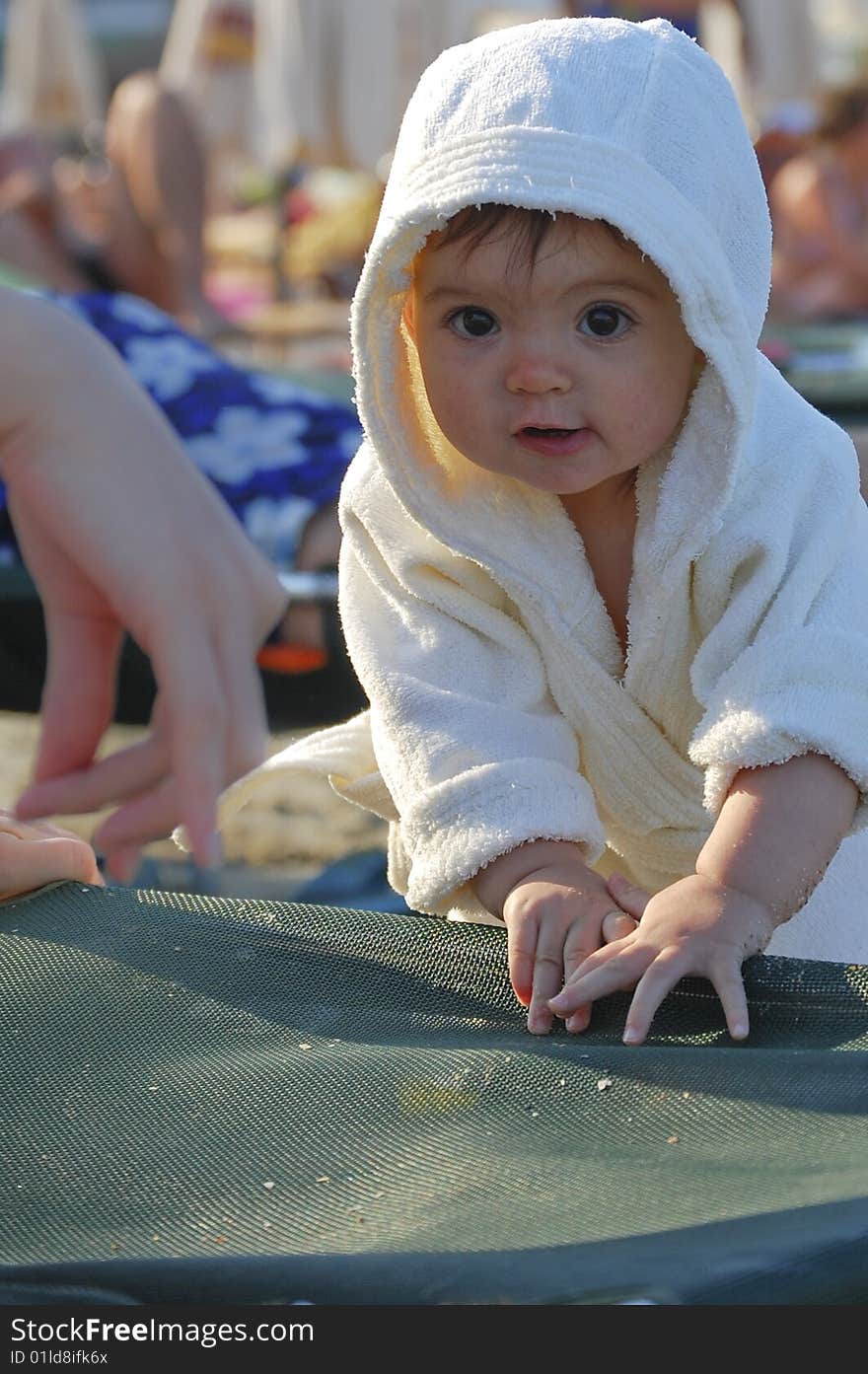 Child in white bathrobe looking at mothers' hand