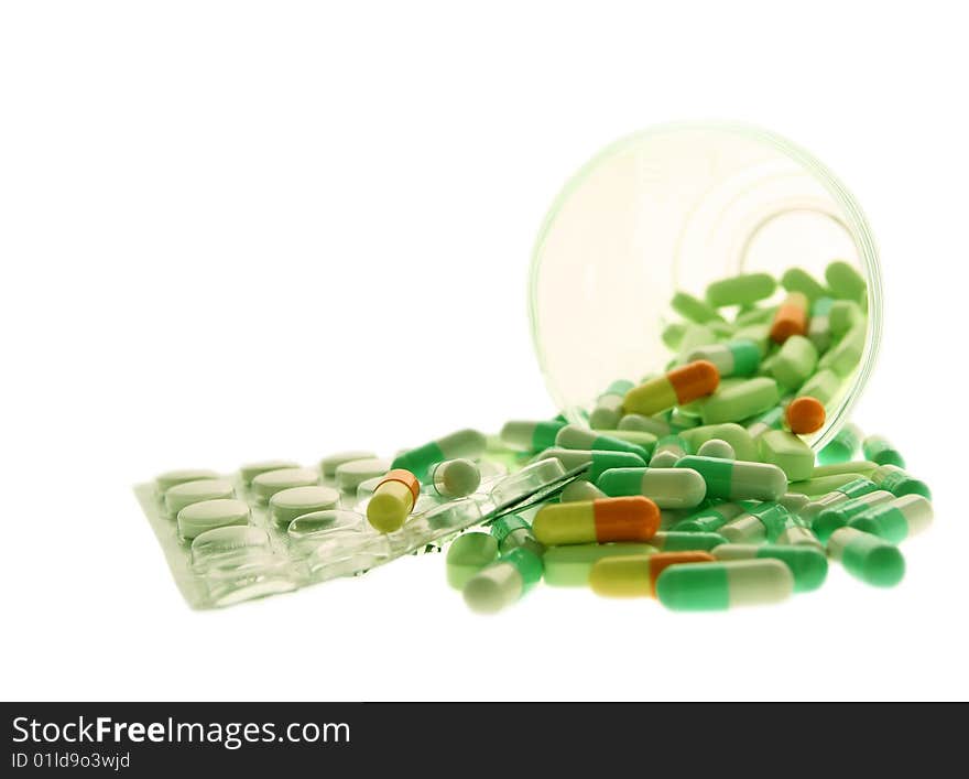 Different pills and tablets are poured out from a glass. Different pills and tablets are poured out from a glass