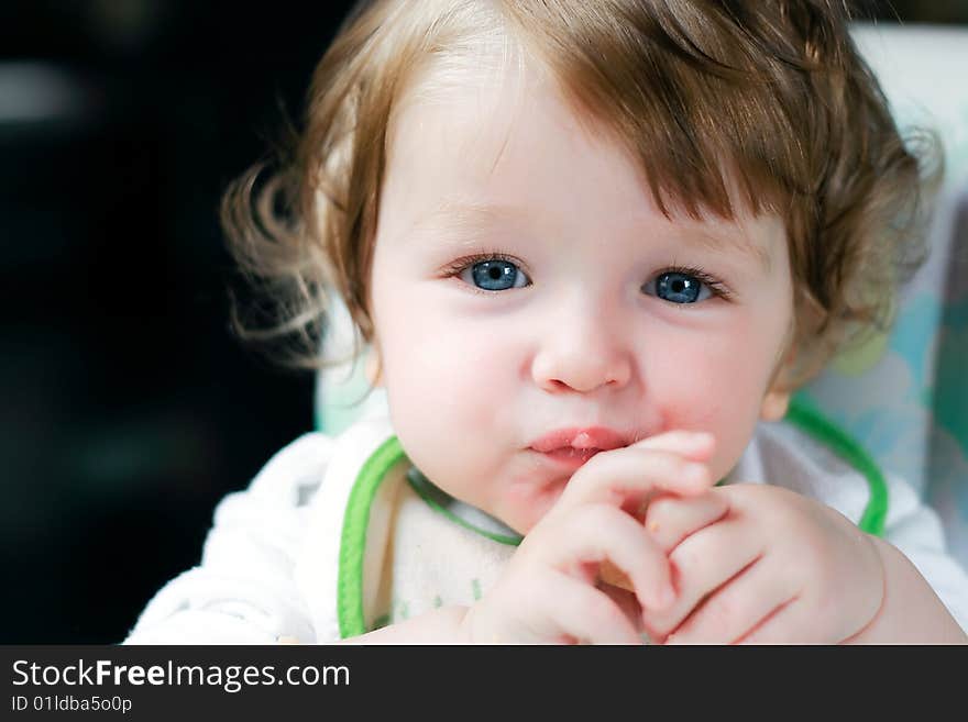 A little blue-eyed child is eating a piece of bread. A little blue-eyed child is eating a piece of bread