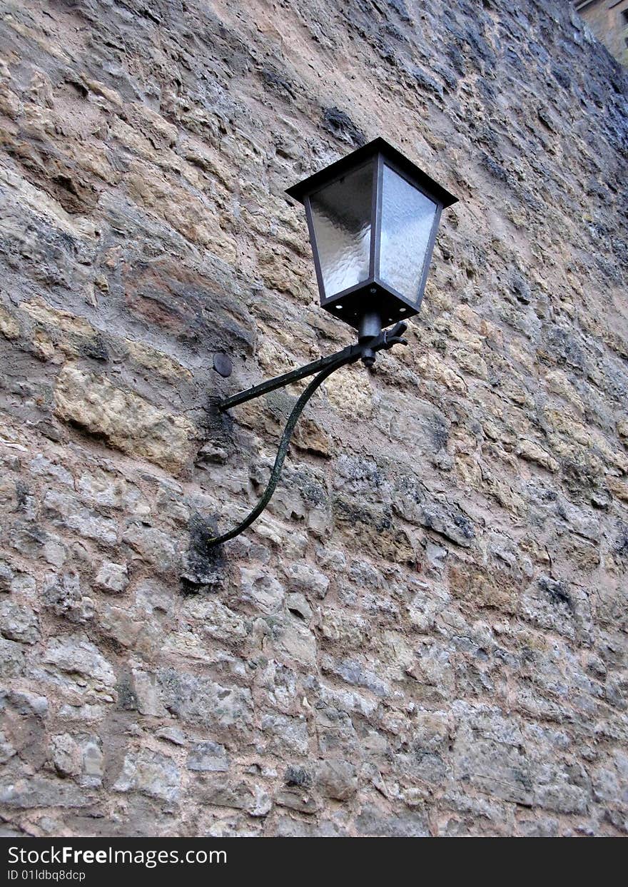 Forged street lamp on the ancient city wall masonry. Forged street lamp on the ancient city wall masonry