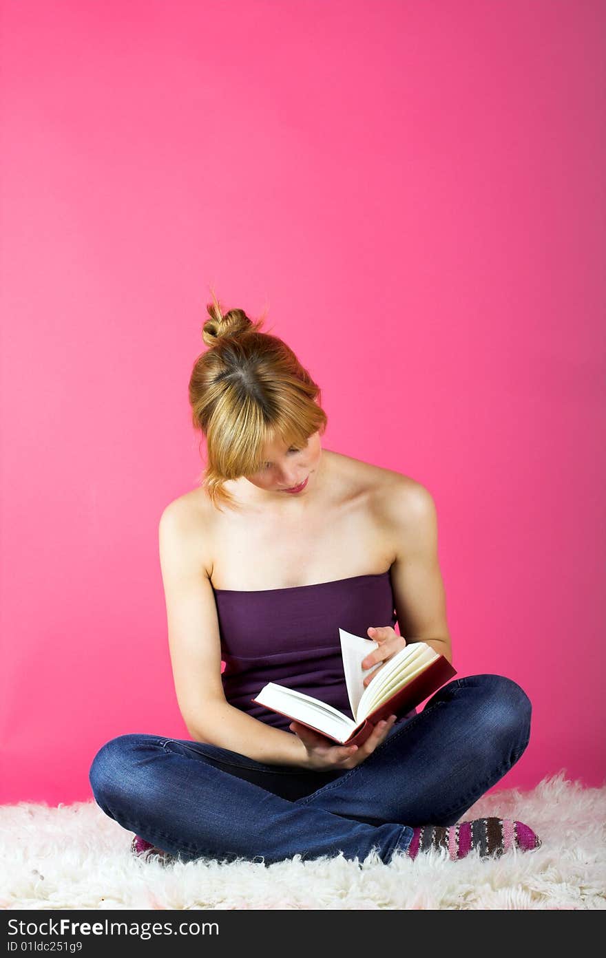 A young beautiful woman is reading on a carpet. A young beautiful woman is reading on a carpet