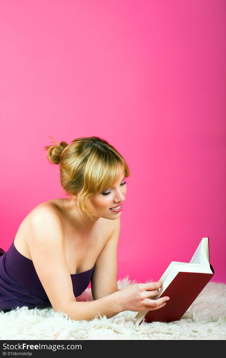 A young beautiful woman is reading on a carpet. A young beautiful woman is reading on a carpet