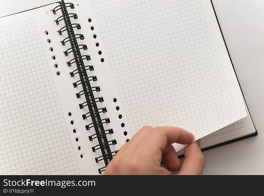 Hand turning page of blank spiral notebook (white background). Hand turning page of blank spiral notebook (white background)