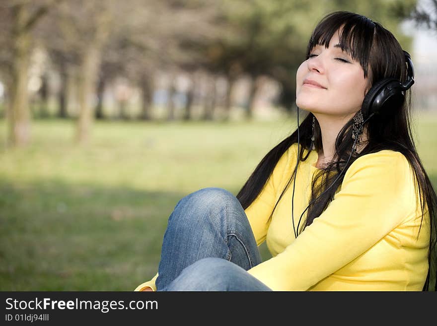 Happy brunette woman with headphones relaxing in park. Happy brunette woman with headphones relaxing in park