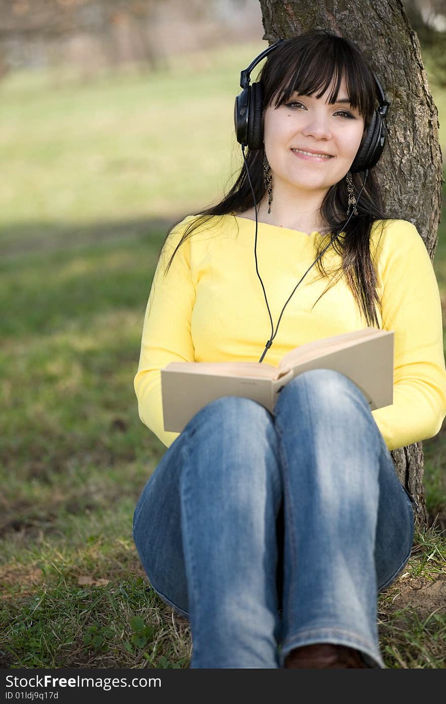 Happy brunette woman reading book in park