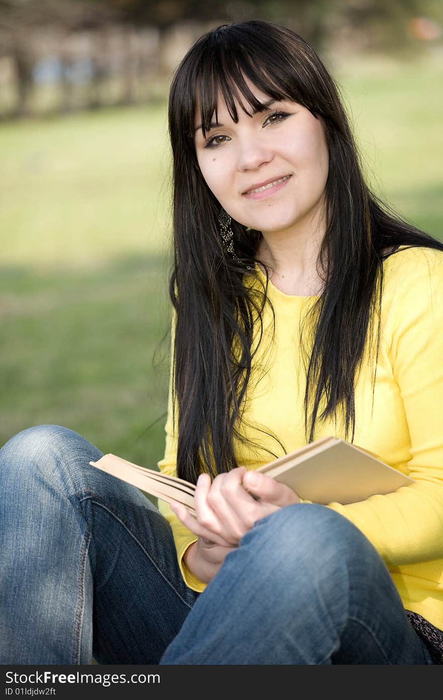 Happy brunette woman reading book in park