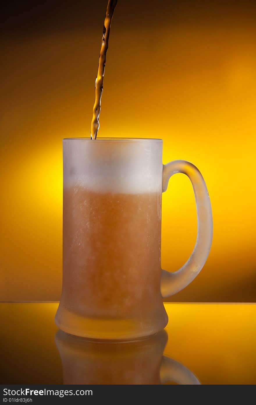 Beer pouring into a glass with yellow background