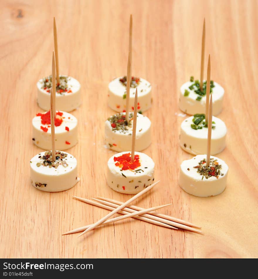 Goat cheese with herbs and toothpicks on wood board