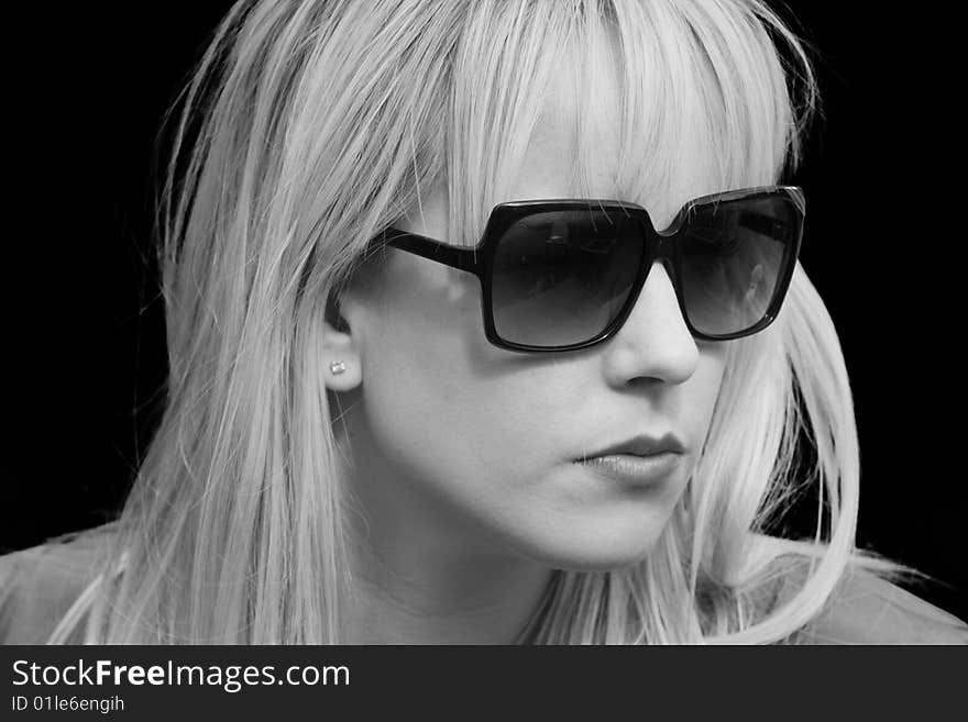 Black and White Portrait of a beautiful blond woman wearing sunglasses against black background. Black and White Portrait of a beautiful blond woman wearing sunglasses against black background