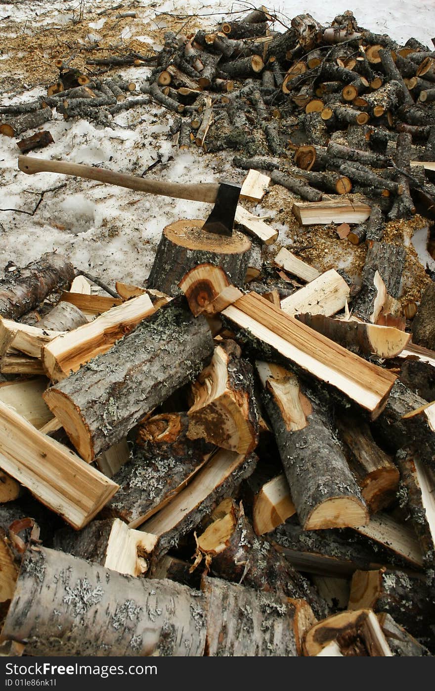 An axe and a pile of chopped wood in winter. An axe and a pile of chopped wood in winter