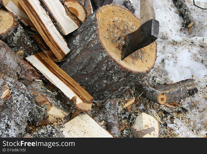 An axe and a pile of chopped wood in winter. An axe and a pile of chopped wood in winter