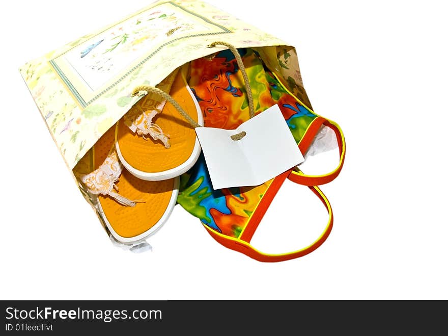 Gift bag with a colorful swimsuit and flip flop shoes in it, isolated on a white background. Gift bag with a colorful swimsuit and flip flop shoes in it, isolated on a white background.