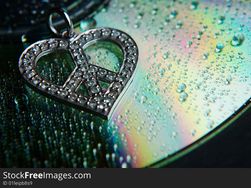 Tiny diamonds highlight this pendant resting upon a CD capturing light and splitting into a rainbow. Water droplets further magnify. Tiny diamonds highlight this pendant resting upon a CD capturing light and splitting into a rainbow. Water droplets further magnify.