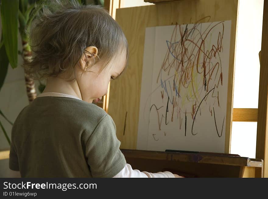 Small artist drawing at a wooden easel. concentrate. Small artist drawing at a wooden easel. concentrate