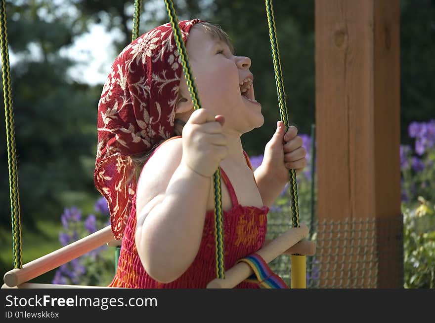 Two-year-old girl on a swing in the garden. Two-year-old girl on a swing in the garden