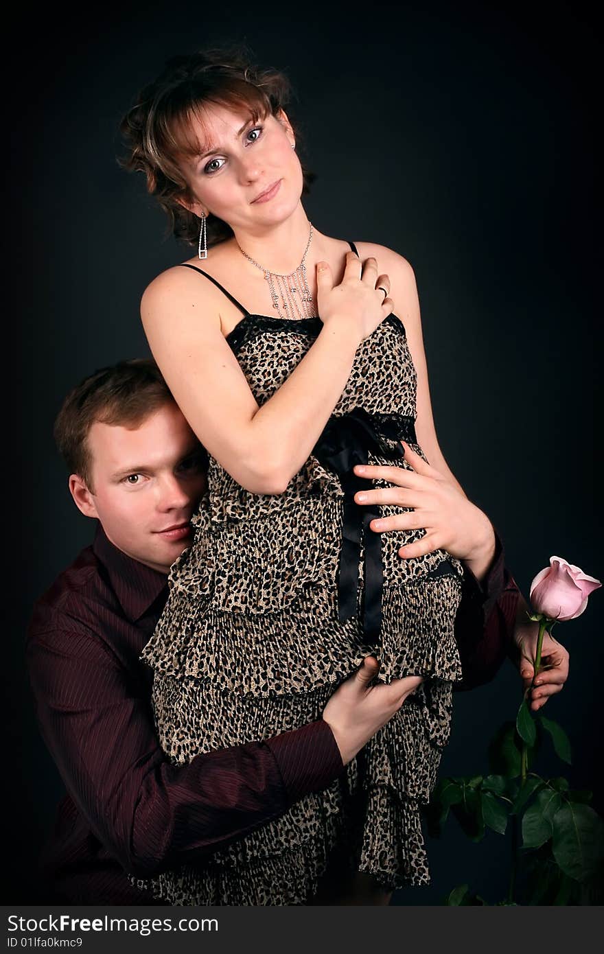 Young beautiful married couple the birth of the second child wait. Dark background. New photos every week