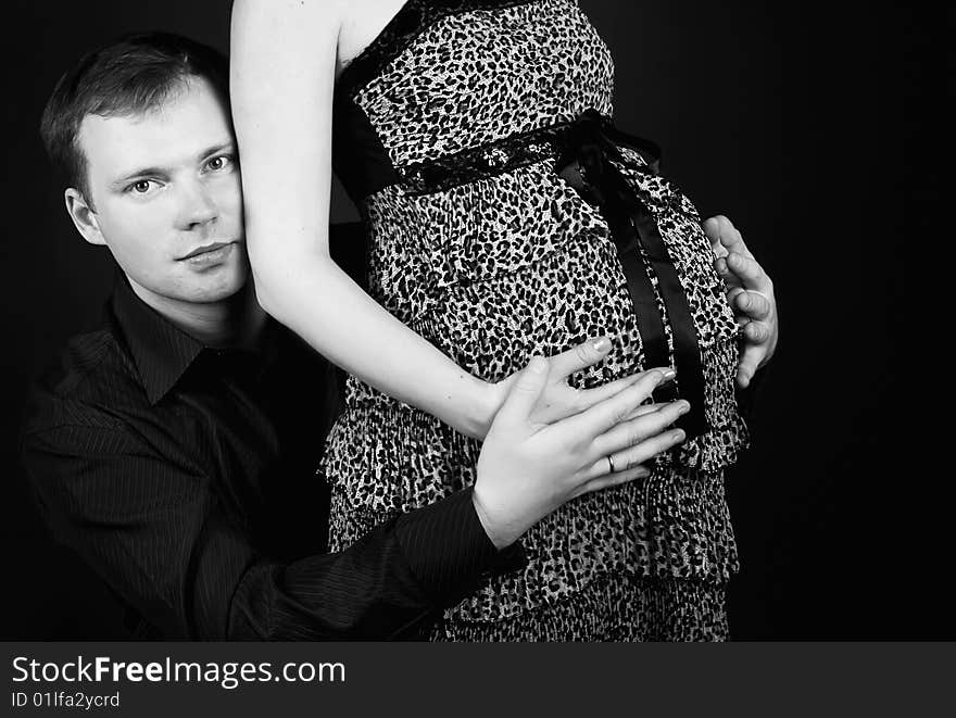 Young beautiful married couple the birth of the second child wait. Dark background. New photos every week