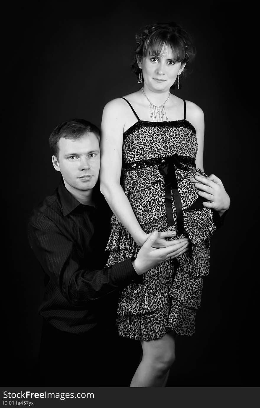 Young beautiful married couple the birth of the second child wait. Dark background. New photos every week