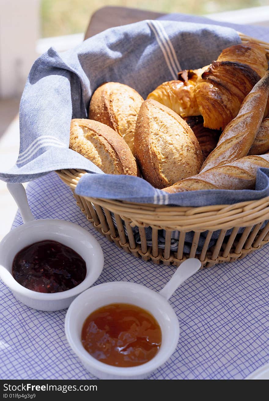 Bread on a wattled tray and two cups with jam