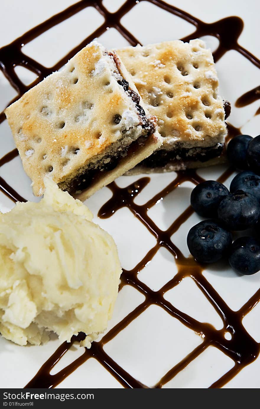 A yummy desert with ice cream, blueberries and chocolate sauce.