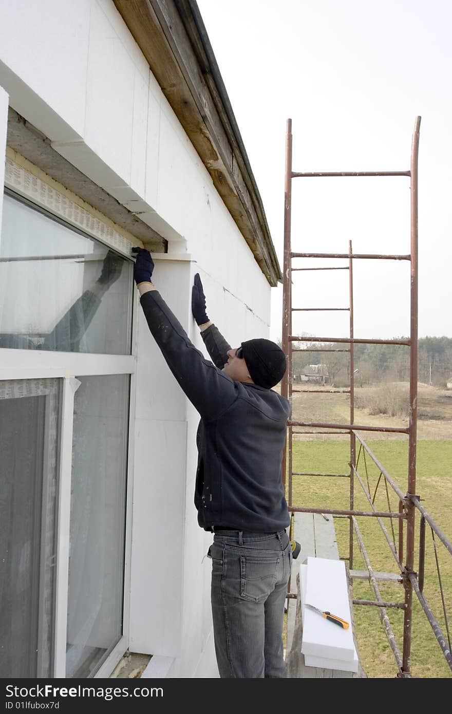 Builder glue polystyrene the plate on wall of the building. check to accuracy of the installation