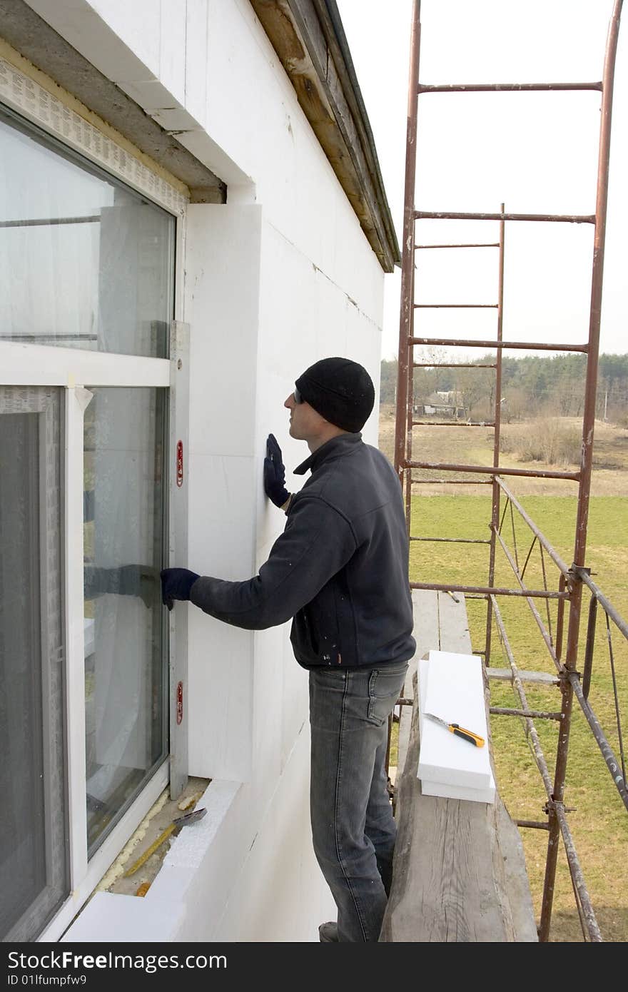 Builder glue polystyrene the plate on wall of the building. check to accuracy of the installation