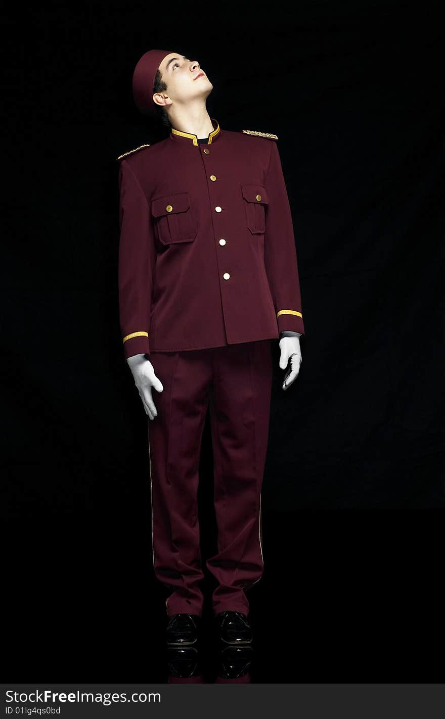 Usher with red uniform stands straight and looks up to a presentation. Usher with red uniform stands straight and looks up to a presentation